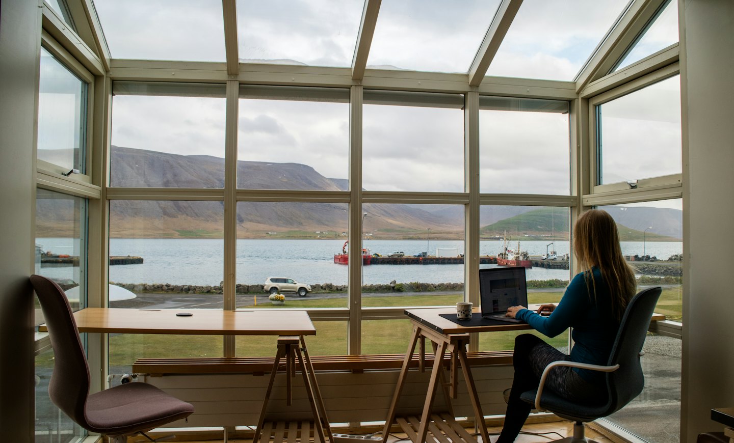 Kvinna arbetar på distans på laptop med utsikt över bukten.