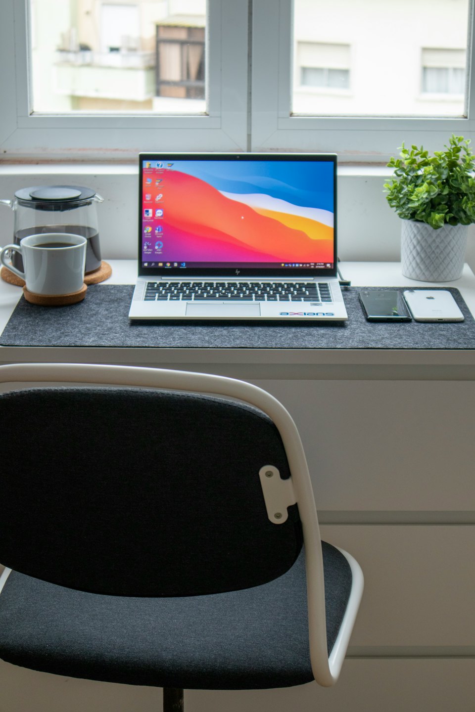 Ett hemmakontorsskrivbord med laptop, kaffe och en växt.